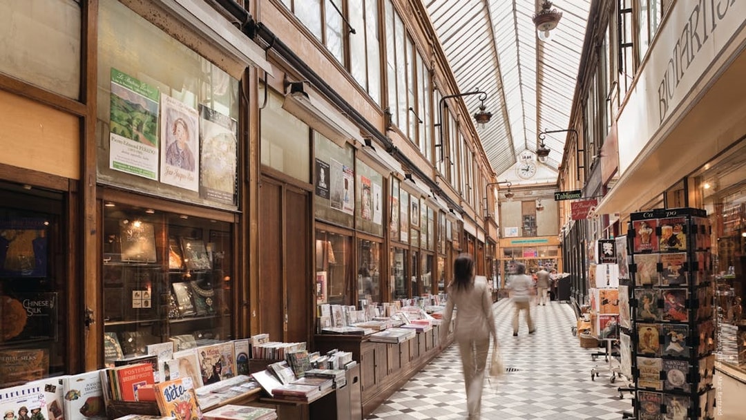 Covered passageway in Paris with shops and people walking, part of The Paris Pass attractions.