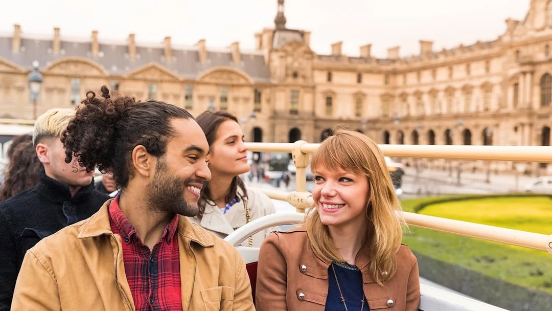 Tourists on an open-top bus near the Louvre Museum in Paris.
