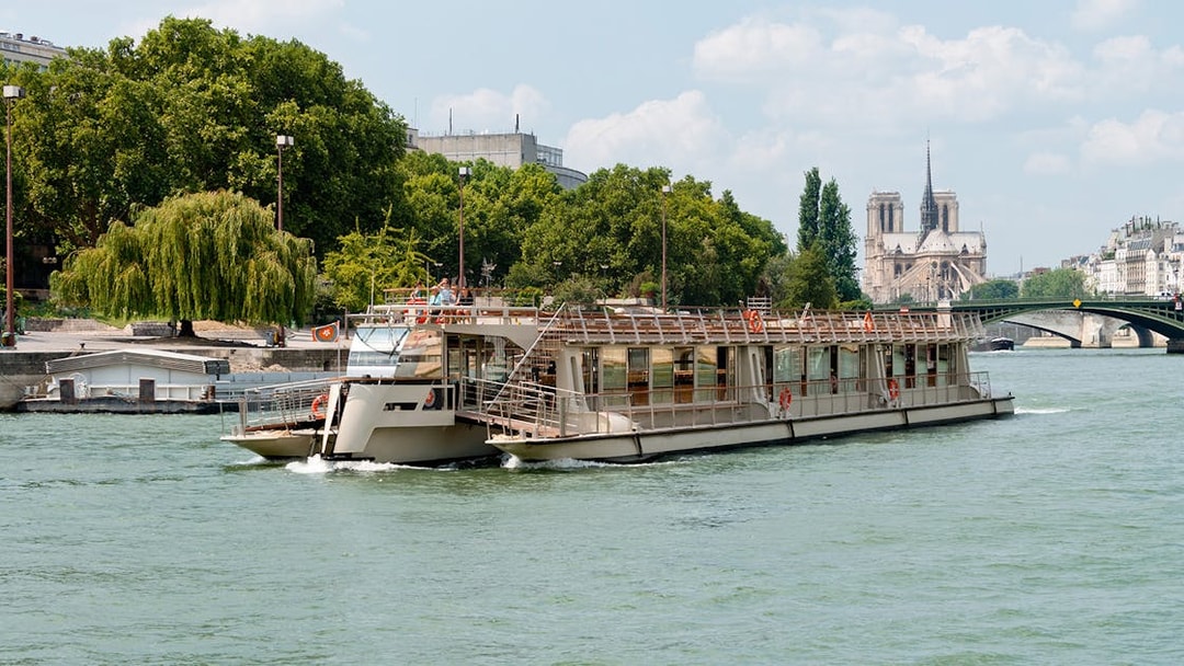 Seine River cruise boat with Notre-Dame Cathedral in the background, Paris.