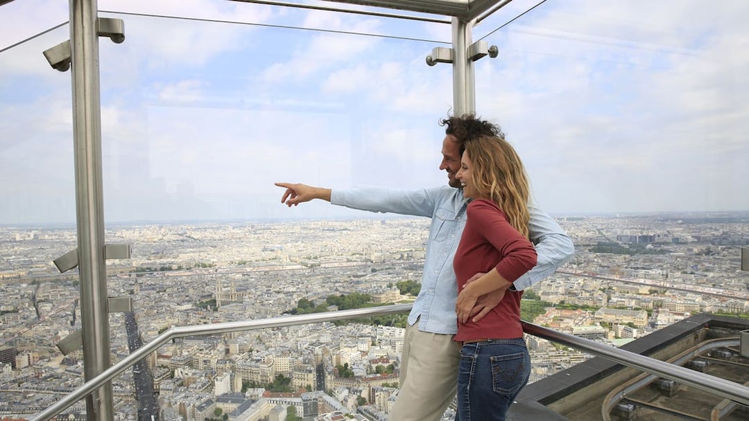 Couple enjoying panoramic view of Paris from Montparnasse Tower observation deck.