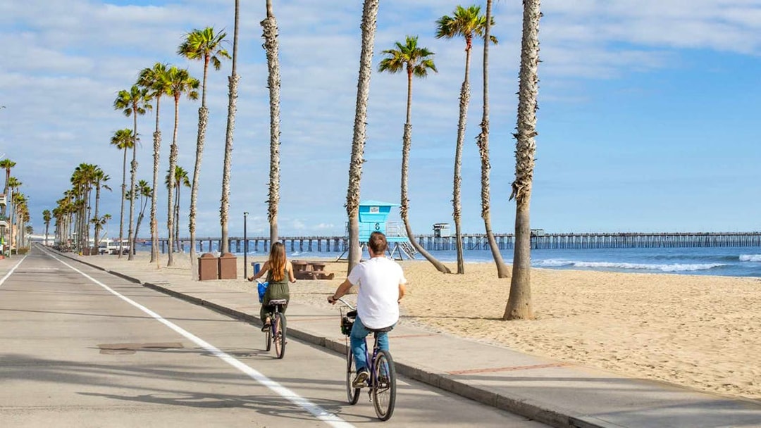 Cyclists on a beachside path with palm trees in San Diego.