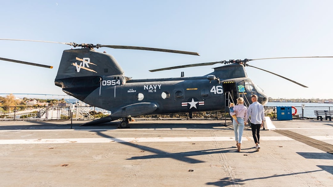 Family exploring a Navy helicopter on the USS Midway Museum deck, San Diego.