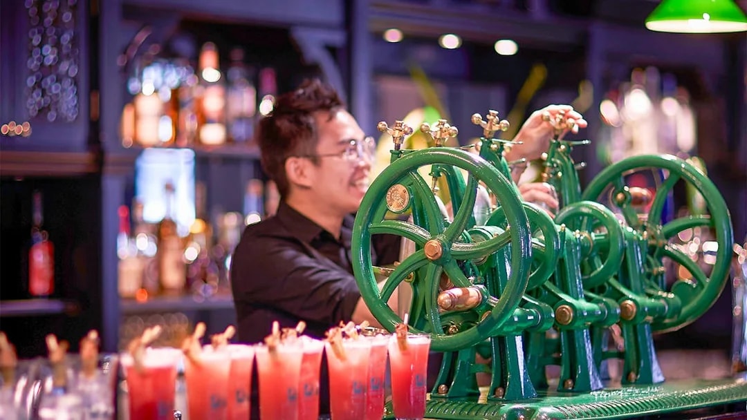 Bartender using vintage machine to prepare drinks at a Singapore bar.