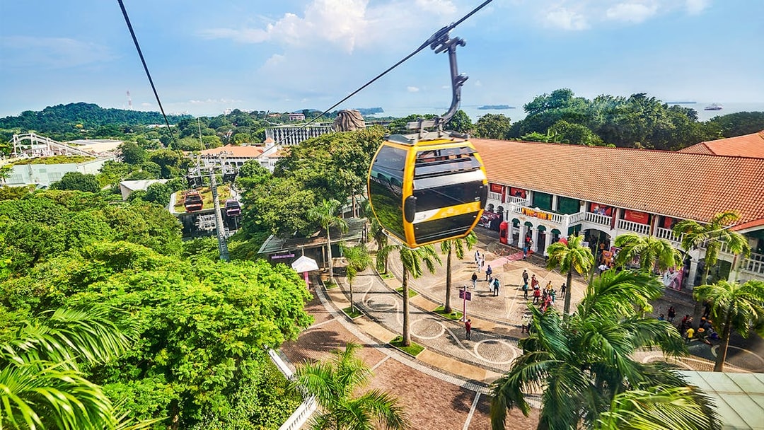 Cable cars over Sentosa Island with Singapore skyline in the background.