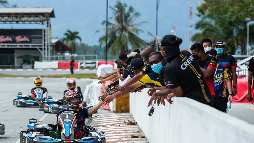 Go-kart racers at Morac Adventure Park in Langkawi high-five spectators.