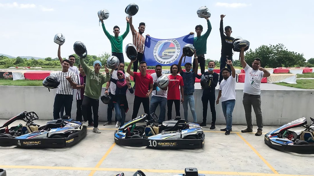 Group celebrating at Go-Kart Langkawi, Morac Adventure Park, holding helmets near karts.