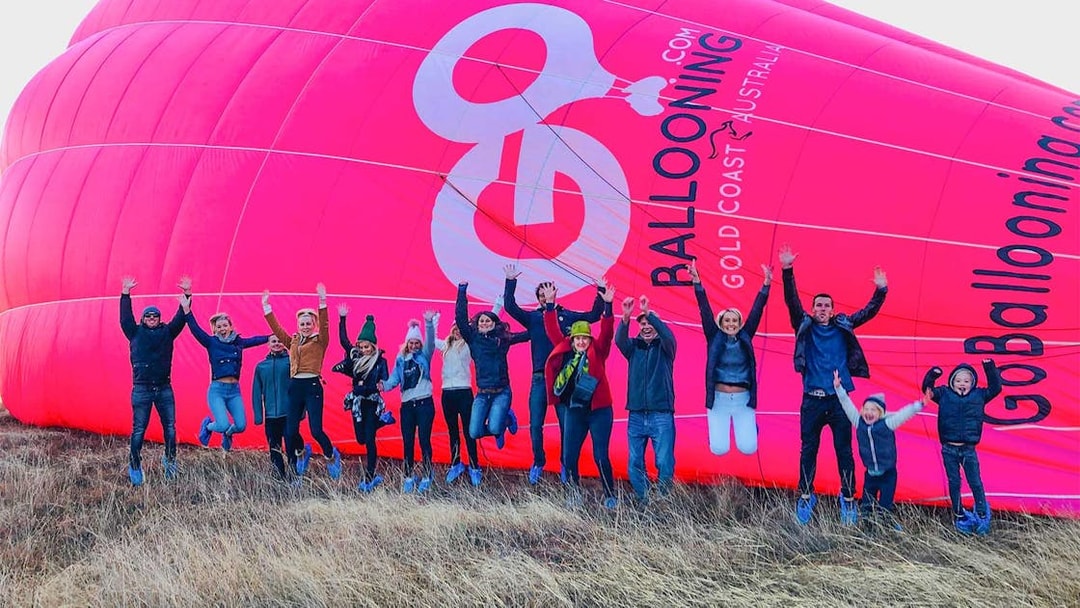 Group jumping in front of a pink hot air balloon in Gold Coast, Australia.
