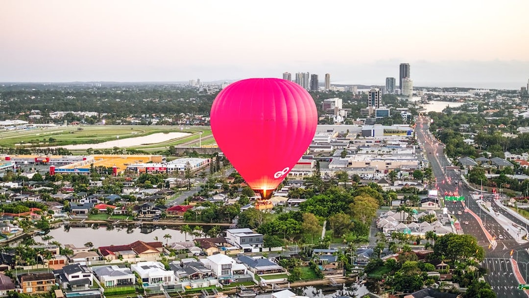 Hot air balloon over cityscape with skyline and river in the background.