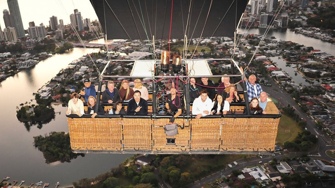 Group enjoying hot air balloon flight over cityscape with optional transfers.