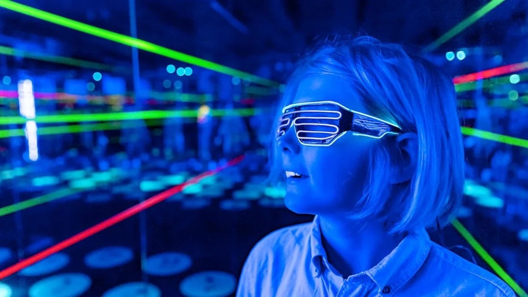 Child wearing LED glasses in a neon-lit room at Infinity Attraction, Gold Coast.