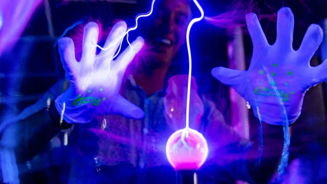 Hands interacting with glowing plasma ball at Infinity Attraction, Gold Coast.