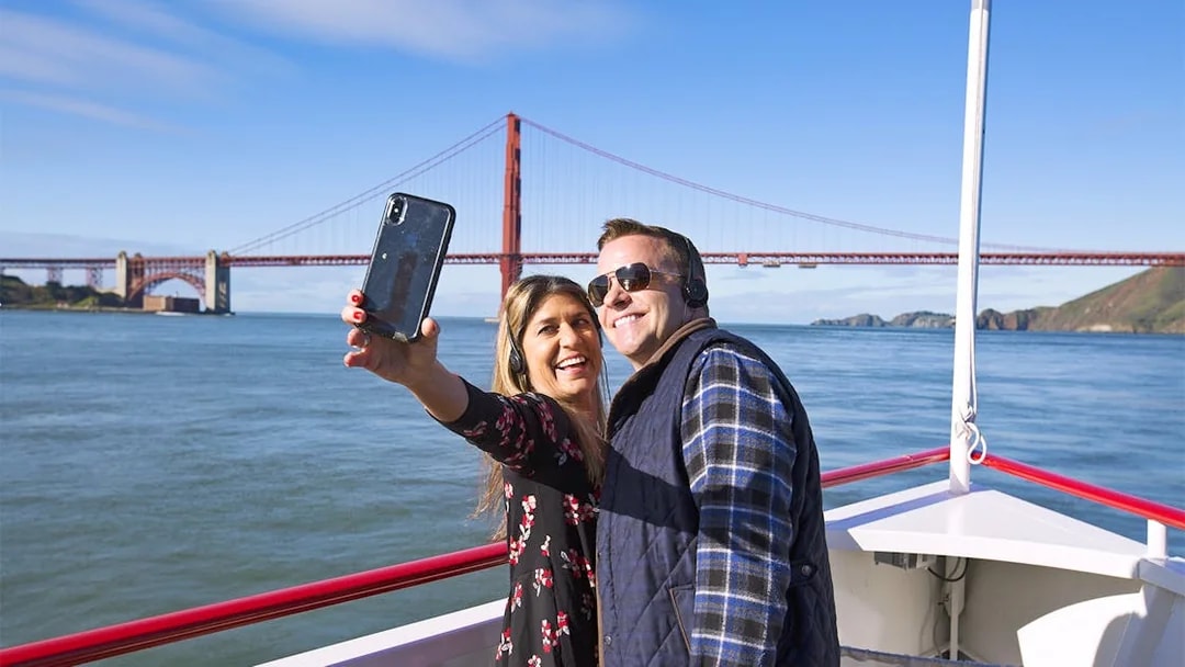 Couple taking a selfie on a Bay Cruise with the Golden Gate Bridge in the background, San Francisco.