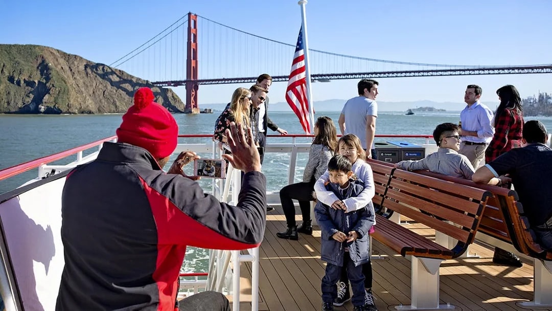People taking photos on a Bay Cruise with the Golden Gate Bridge in San Francisco, USA.