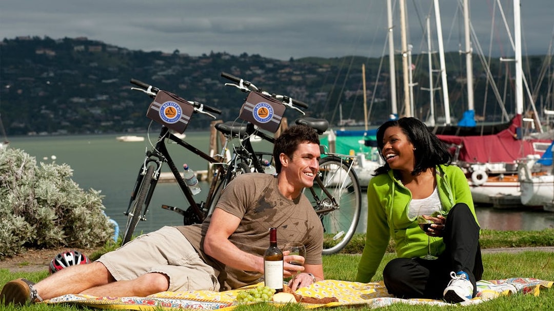 Couple enjoying a picnic by the bay with bikes on the Golden Gate Bridge to Sausalito tour.