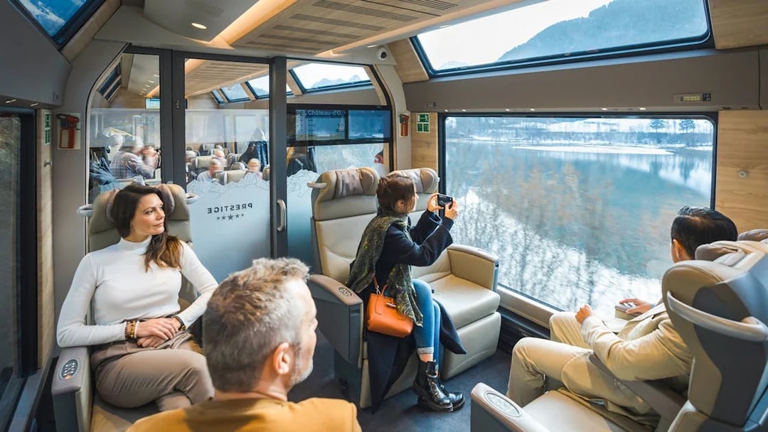 Passengers enjoying views on the GoldenPass Express train from Montreux to Interlaken.