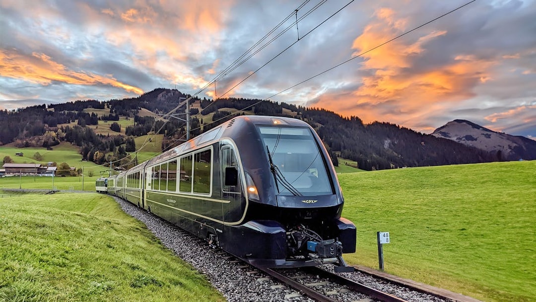 GoldenPass Express train traveling through scenic Swiss countryside near Interlaken at sunset.
