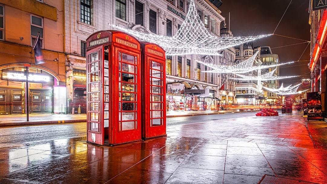 Red phone booth near Leicester Square with Christmas lights and decorations.