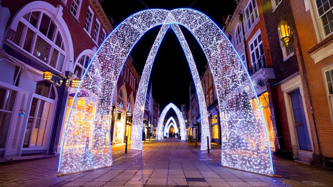 London street adorned with illuminated Christmas arches at night.