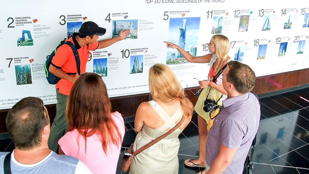 Group of tourists learning about Bitexco Financial Tower at Saigon Skydeck exhibit.