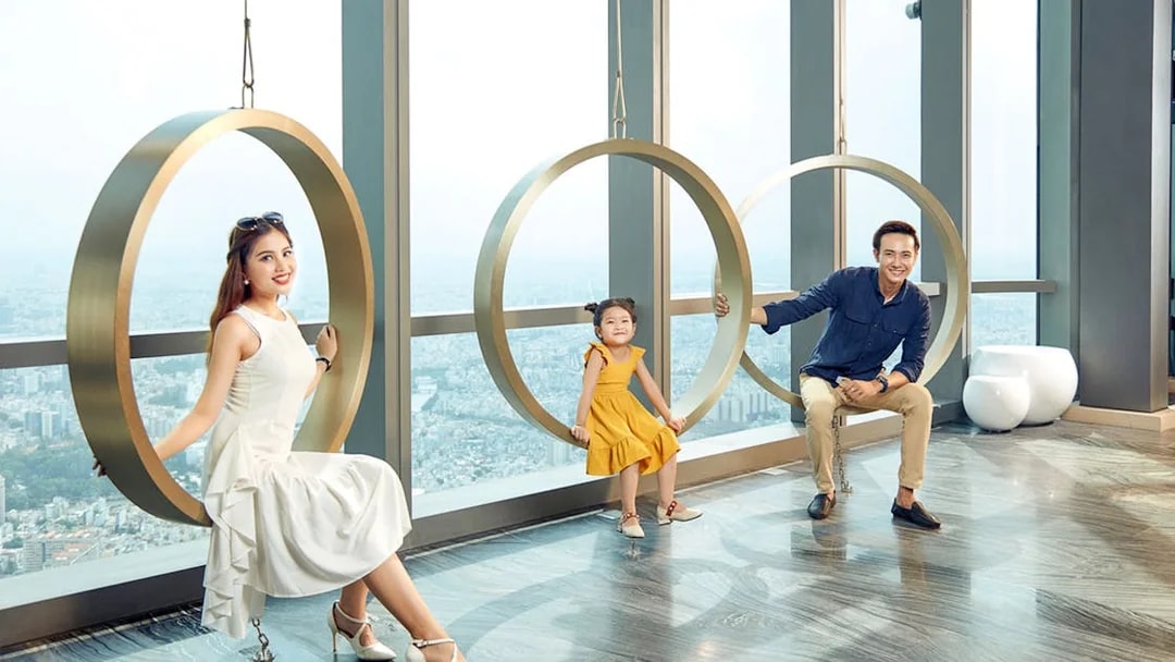 Visitors enjoying circular swings at Saigon Skydeck, Bitexco Financial Tower, with city view.