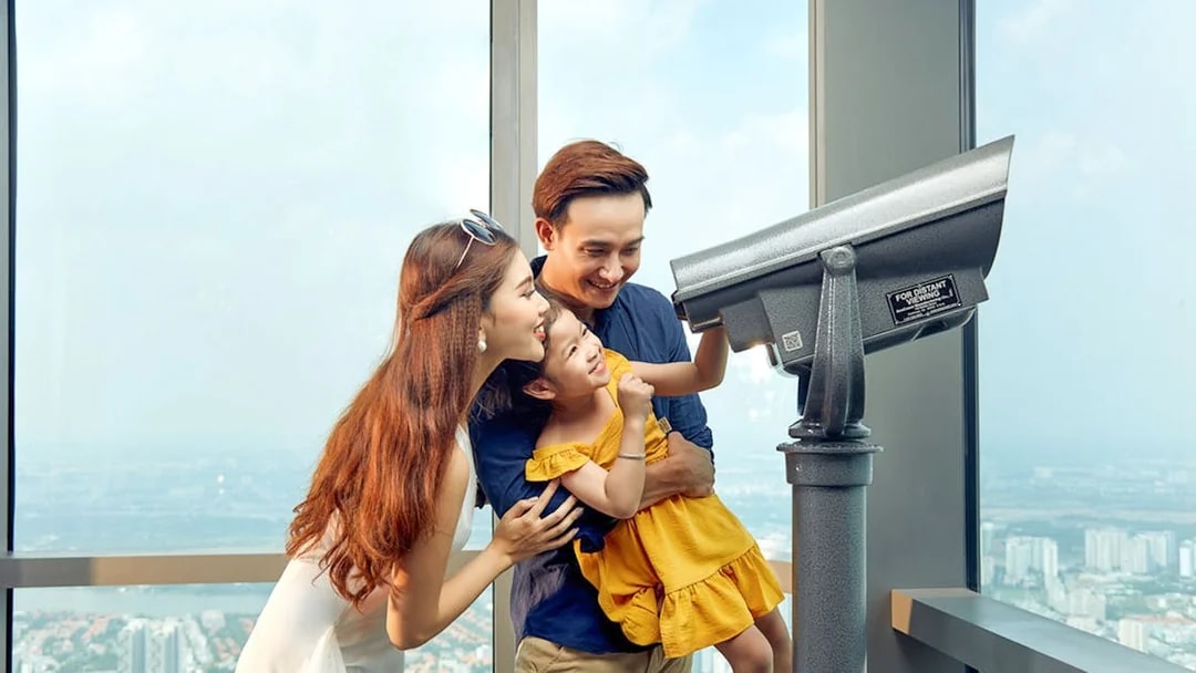 Family enjoying the view through a telescope at Saigon Skydeck, Bitexco Financial Tower.