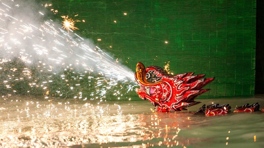 Dragon puppet emitting sparks during Golden Water Puppet Show in Vietnam.