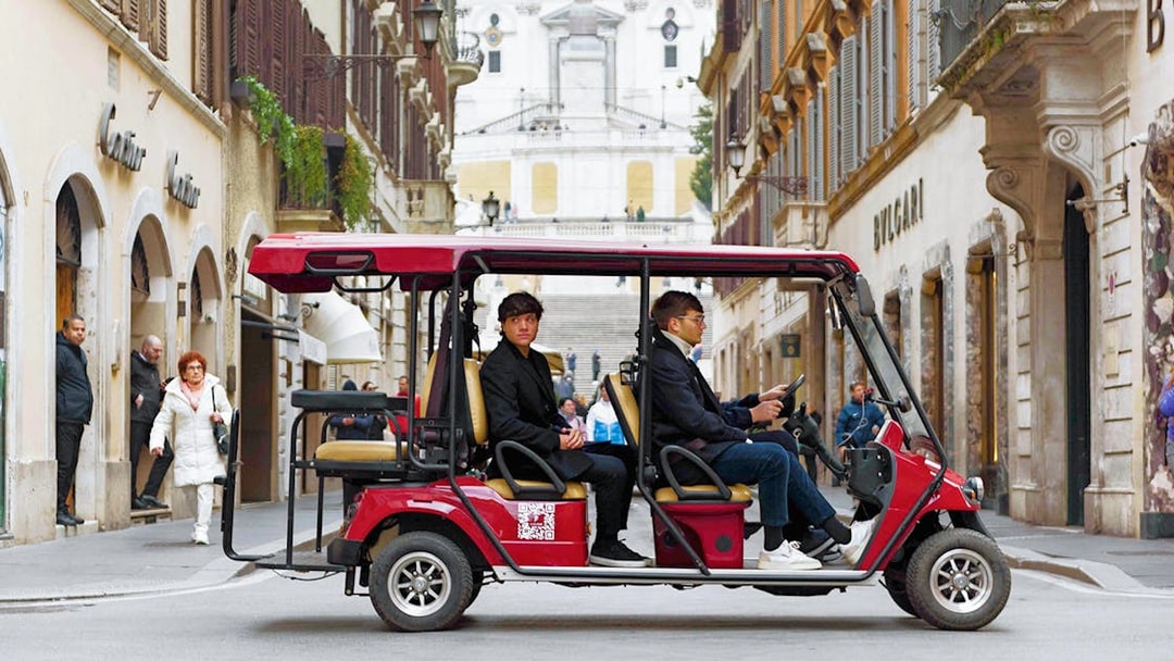 Golf cart tour passing through a street in Rome with the Spanish Steps in the background.