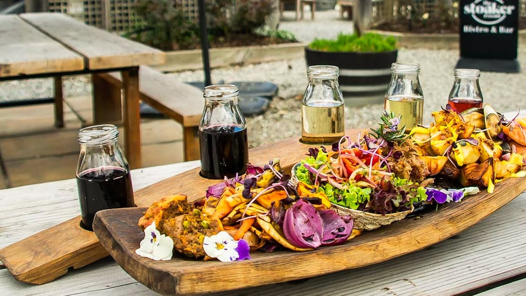 Gourmet platter with assorted vegetables and wine glasses on a Queenstown tour.