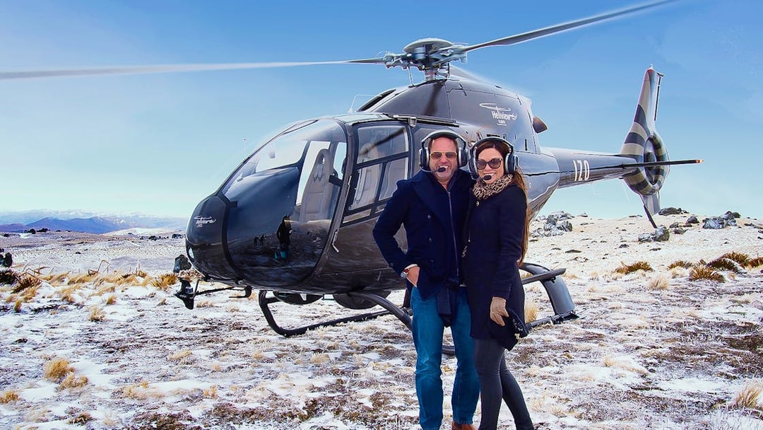 Helicopter landing on snowy terrain during Queenstown gourmet food and wine tour.