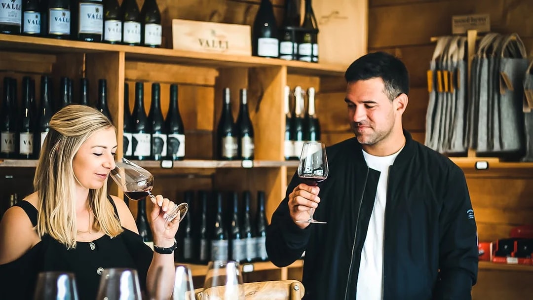 Wine tasting experience in Queenstown winery with two people sampling red wine.