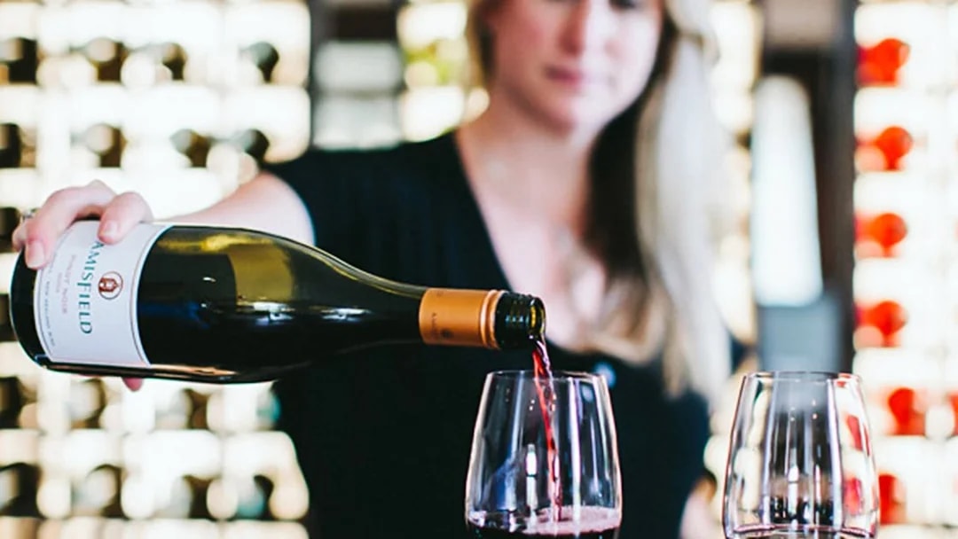 Pouring red wine into glasses on a Queenstown gourmet food and wine tour.