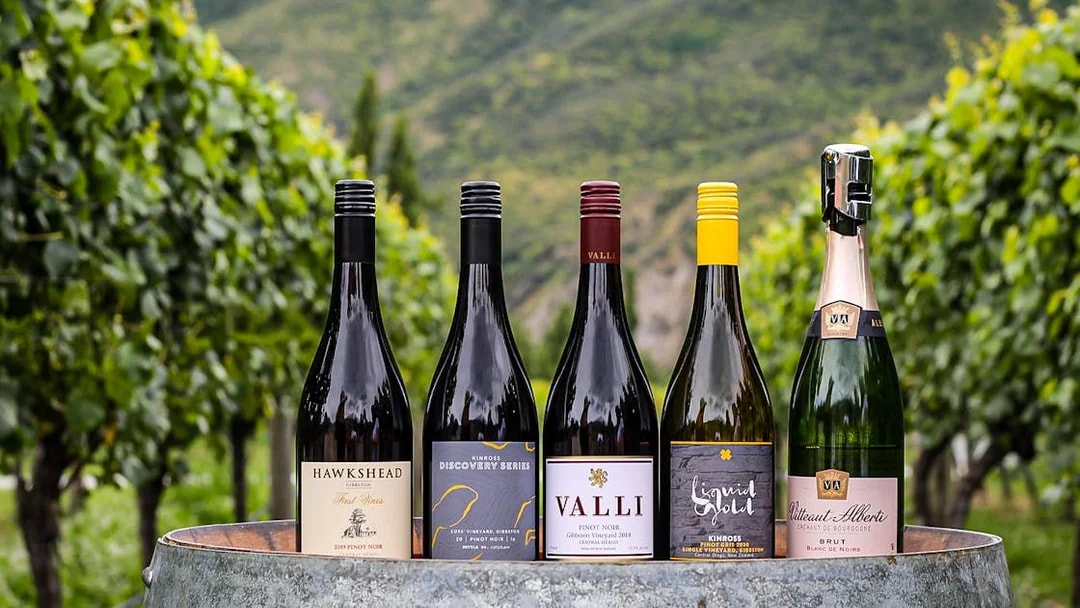 Bottles of wine on a barrel in a vineyard during a Queenstown gourmet food and wine tour.