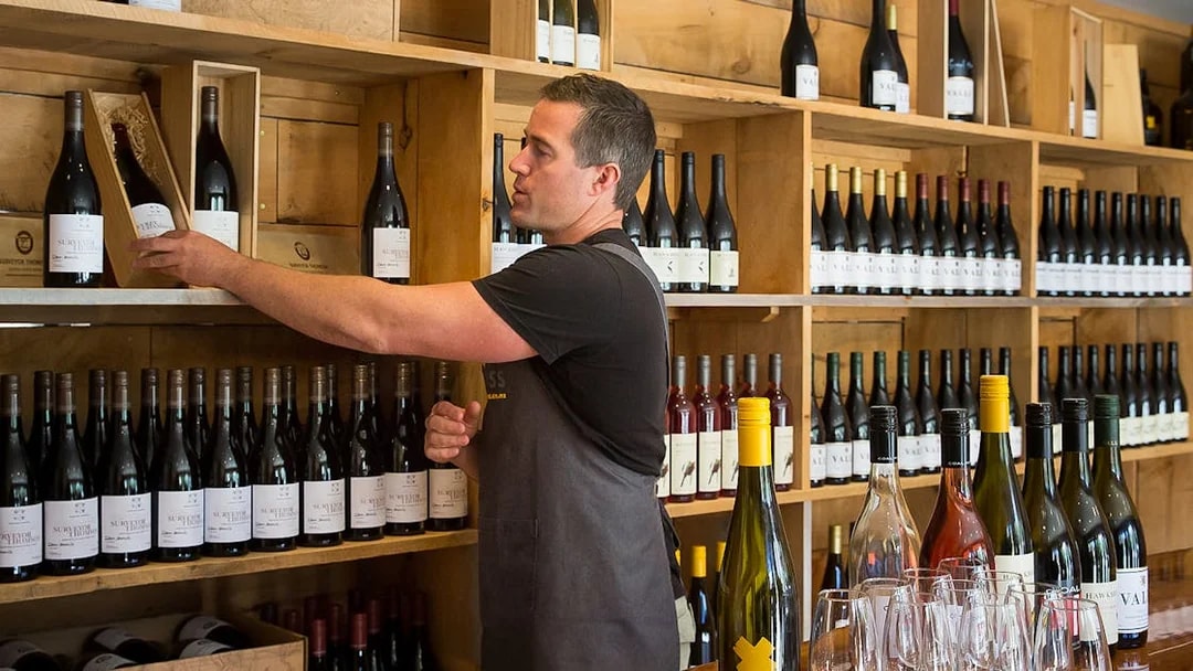 Man selecting wine bottle in Queenstown winery during gourmet food and wine tour.