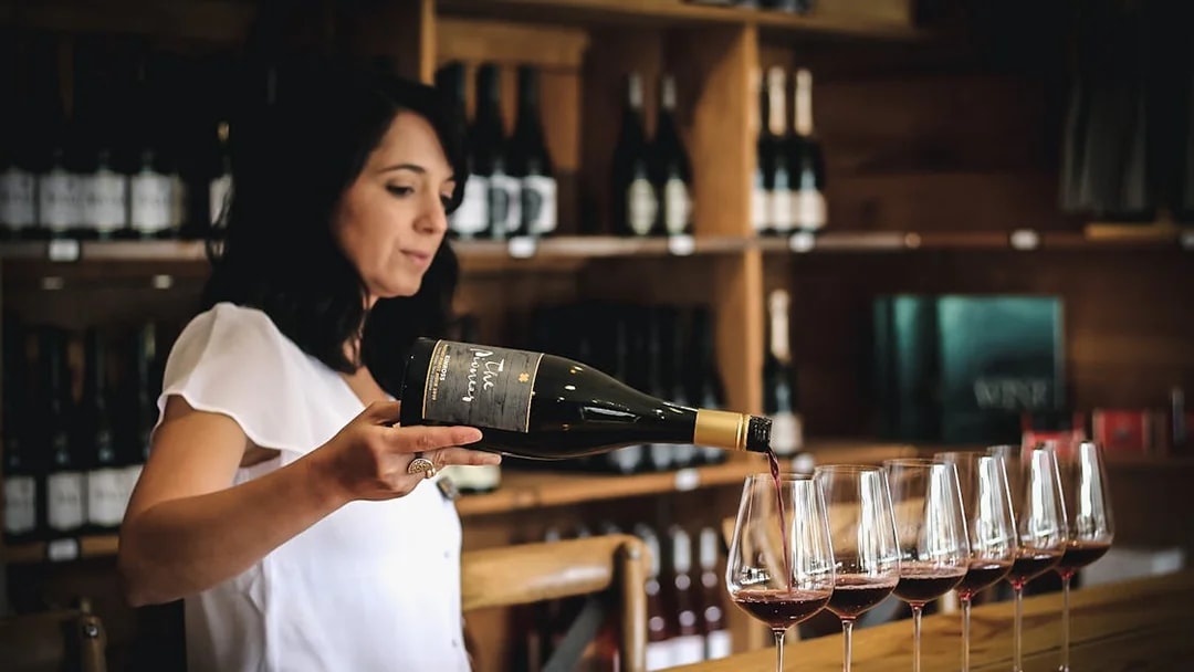 Pouring red wine into glasses during Queenstown gourmet tour.