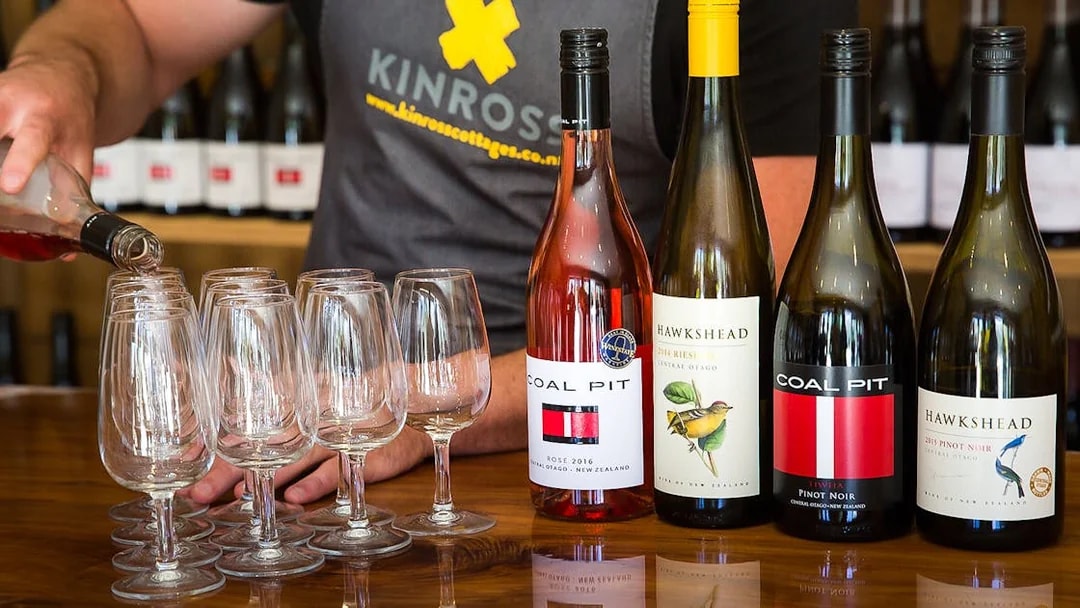 Pouring wine at a tasting with Coal Pit and Hawkshead bottles in Queenstown.