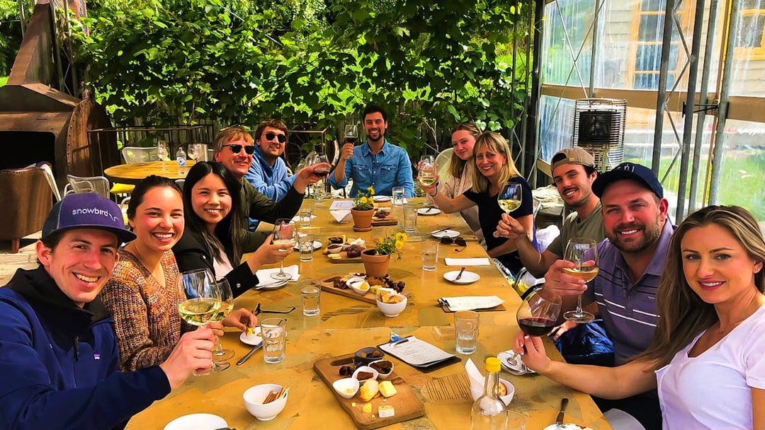 Group enjoying wine and cheese at a vineyard on a Queenstown gourmet tour.