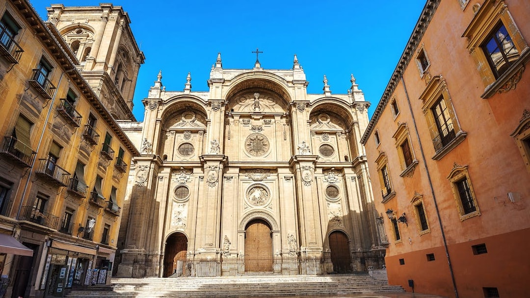 Granada Cathedral facade with surrounding buildings on a sunny day.