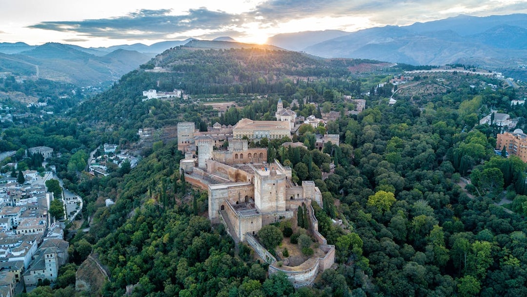 Aerial view of the Alhambra surrounded by lush greenery in Granada, Spain.