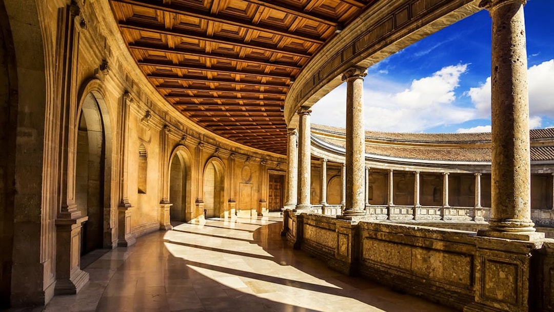 Alhambra's circular courtyard with stone columns and arches in Granada, Spain.