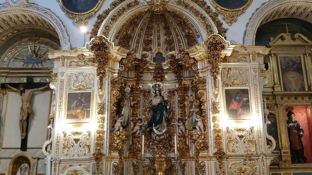 Altar with ornate gold detailing and religious statues inside Granada Cathedral.
