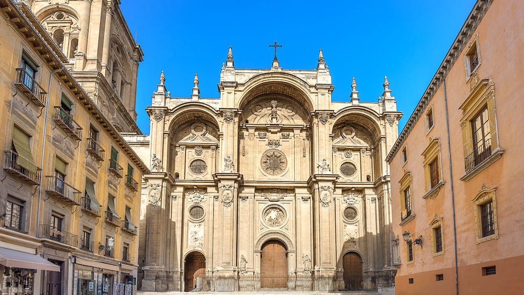 Granada Cathedral entrance with ornate facade and surrounding historic buildings.