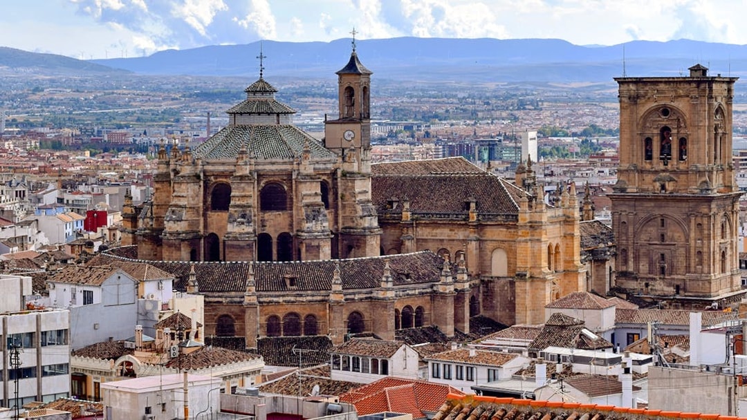 Granada Cathedral with cityscape and mountains in the background, Granada, Spain.