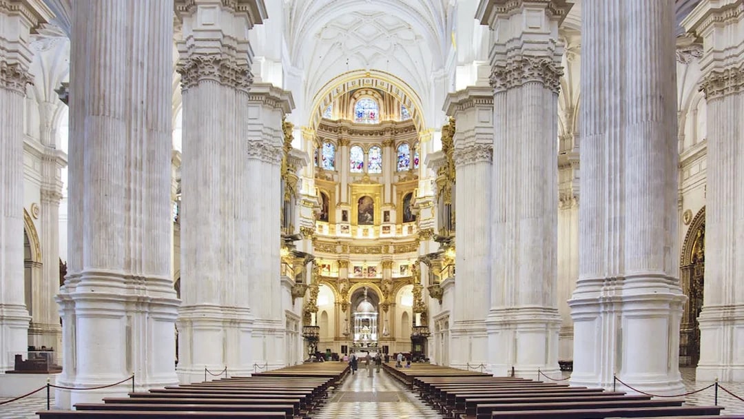 Granada Cathedral interior with ornate columns and stained glass windows.