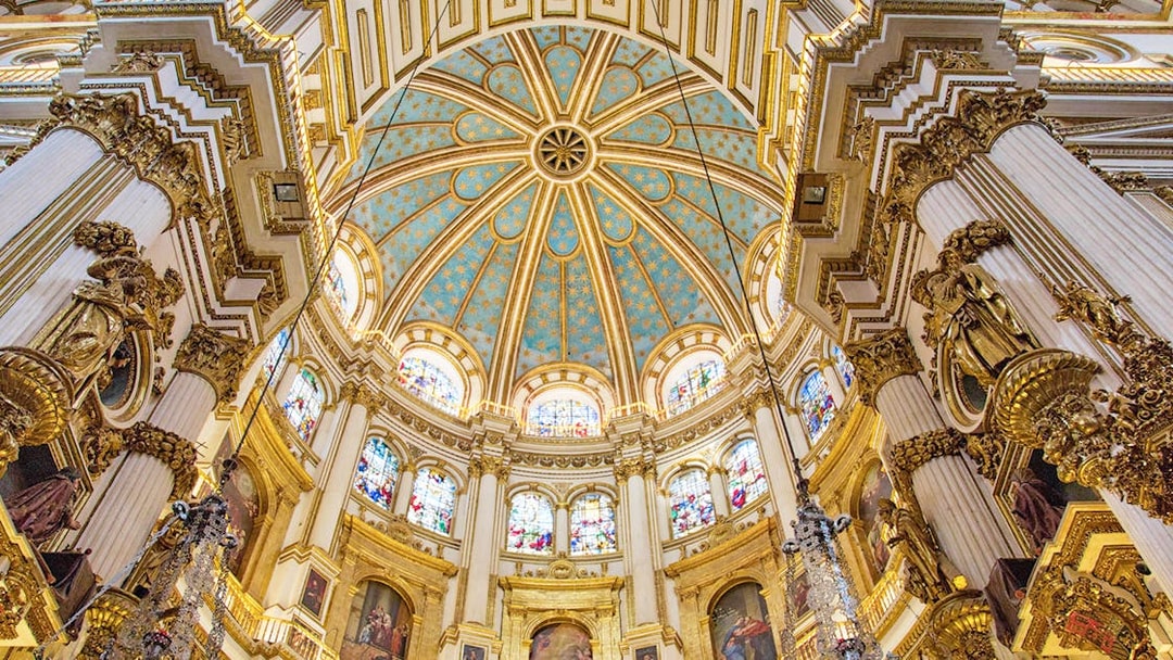 Granada Cathedral interior with ornate columns and stained glass windows.
