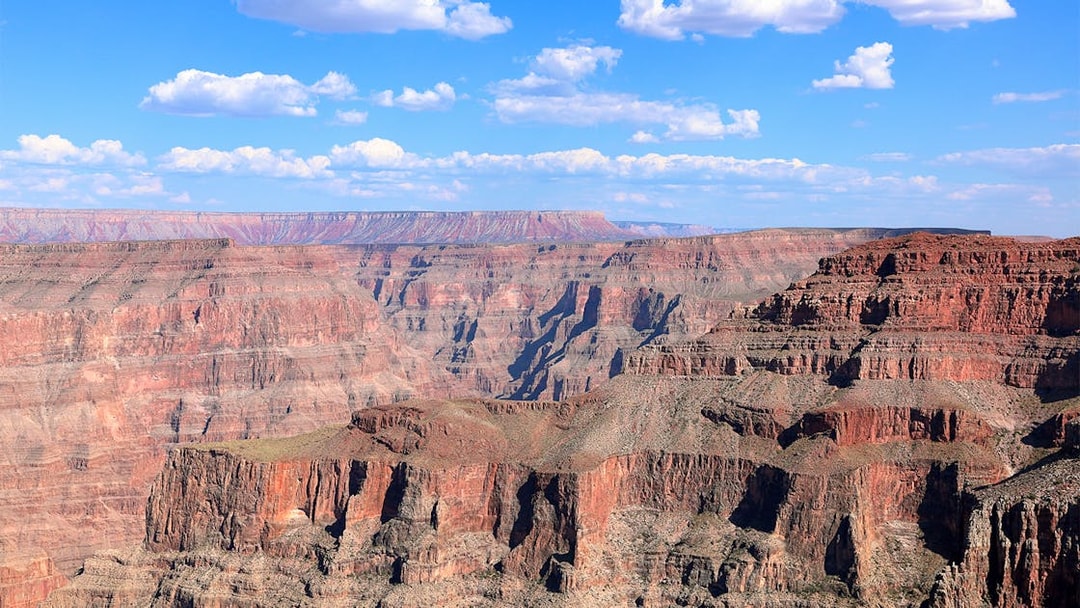 Grand Canyon West Rim with layered rock formations under a blue sky.