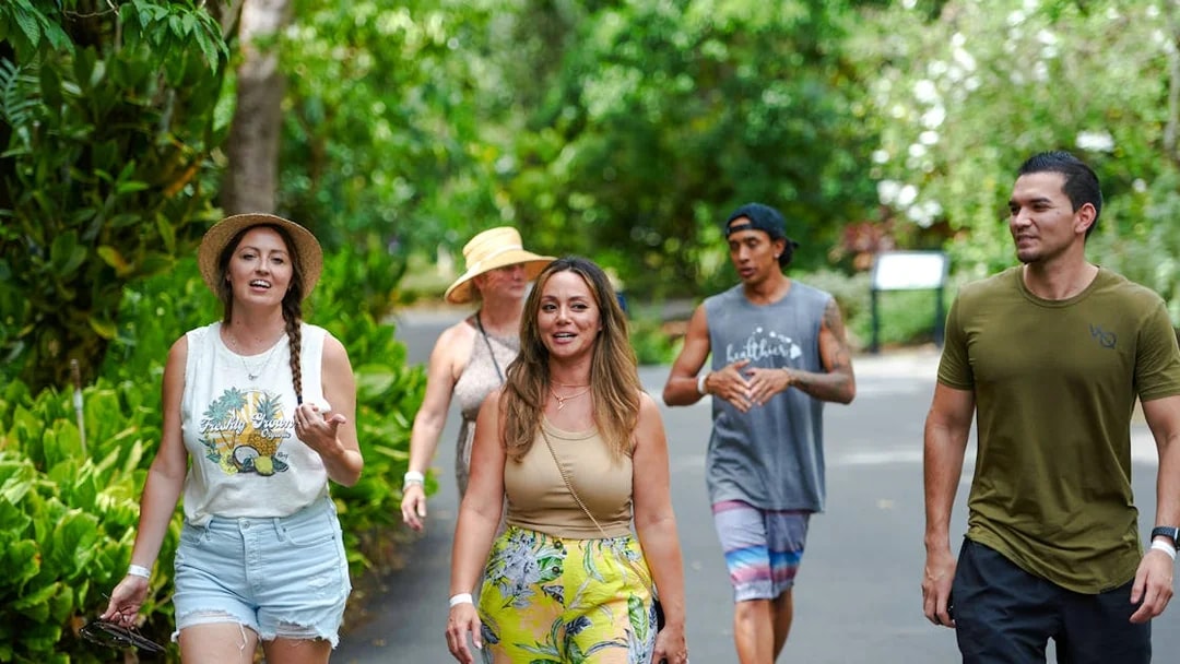 Five people walking on a paved path surrounded by lush greenery in Oahu, Hawaii.
