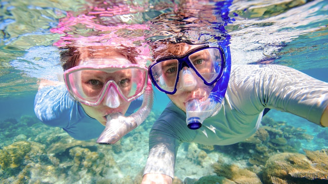 Couple snorkeling near coral reefs in clear waters, Oahu, Hawaii.
