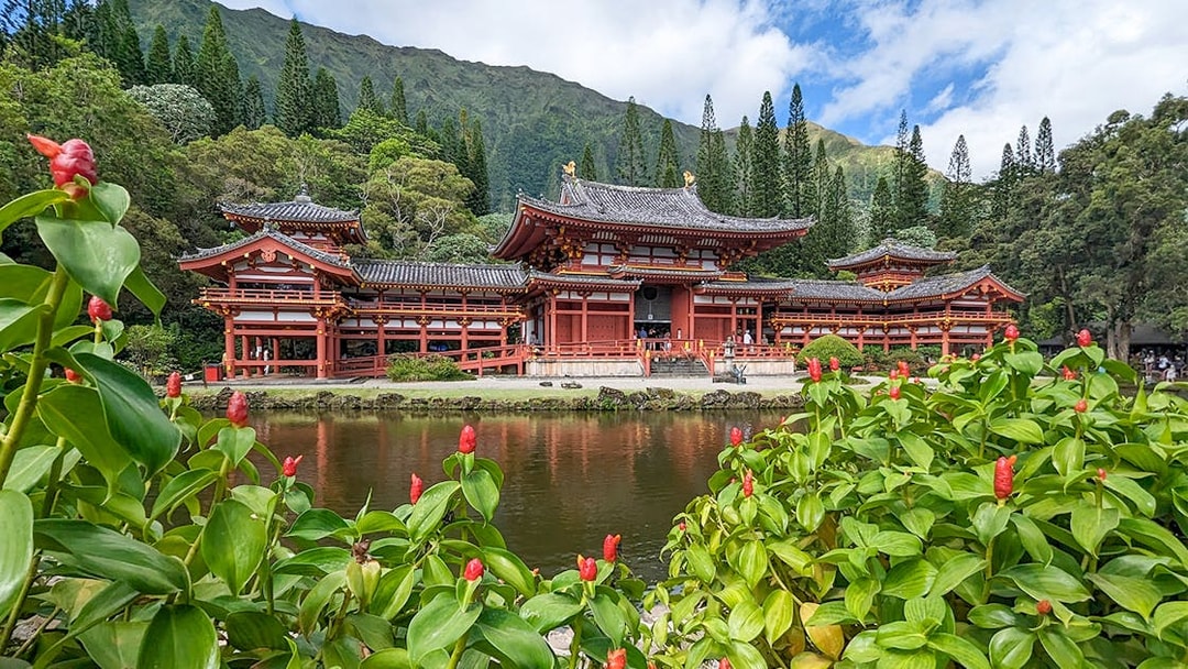 Byodo-In Temple in Oahu, Hawaii with lush greenery and pond in foreground.