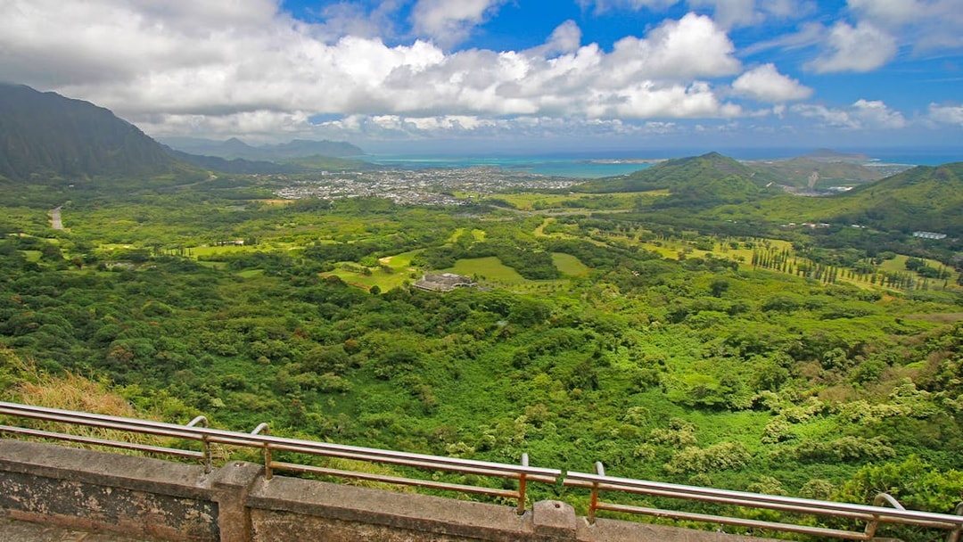 Windward coast of Oahu view from Nuuanu Pali Lookout, showcasing lush green landscape and ocean.