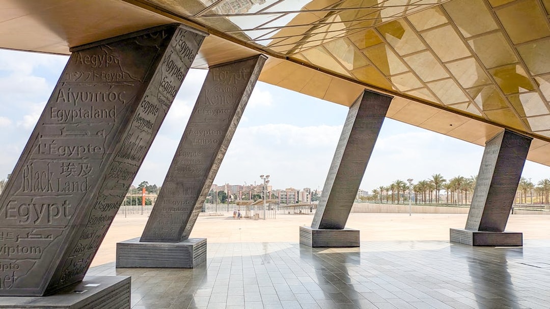 Grand Egyptian Museum entrance with engraved pillars and city view.